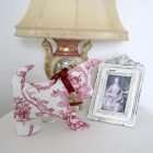 Dog Adelaide in a setting, on a table in front of a lamp and a Renaissance style frame.