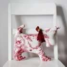 Dog in red toile with a red ribbon around the neck.