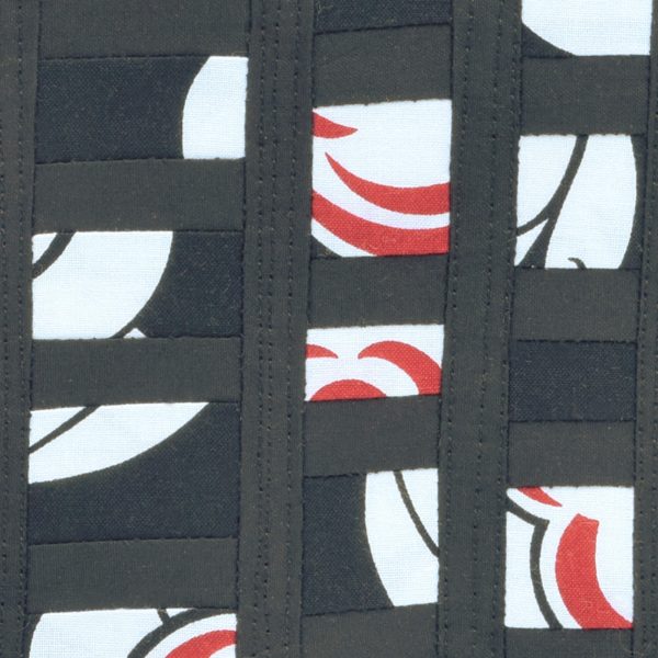 Détail de la pièce d'art textile En petits morceaux. Parties blanche et rouge sur fond noir.
