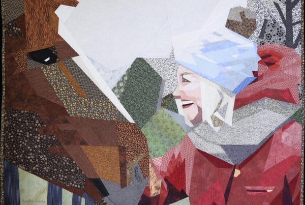 La rencontre textile art piece showing a smiling girl face to face with the head of a horse.