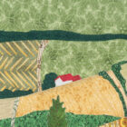 Détail de la pièce d'art textile Le 3e rang. Petite maison blanche au toit rouge entre les vallons et les champs à la campagne.