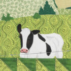 Détail de la pièce d'art textile Le 3e rang. Une vache noire et blanche est en premier plan dans un champs vert où l'on voit des sapins derrière.