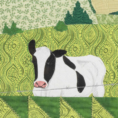 Détail de la pièce d'art textile Le 3e rang. Une vache noire et blanche est en premier plan dans un champs vert où l'on voit des sapins derrière.