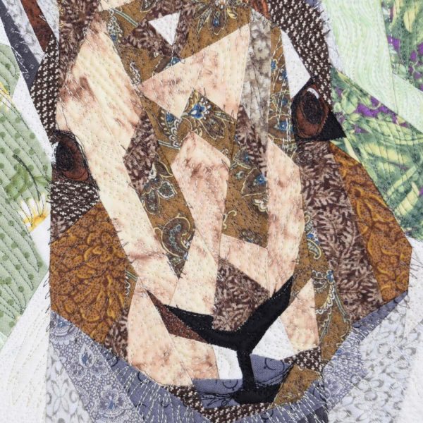 Detail of the textile art piece Mister Sylvestre. Face of the hare. We see the pieces of different fabrics and the stitching.