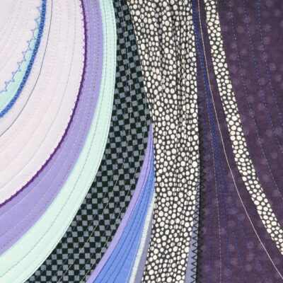 Détail du tableau d'art textile Moraine. Pièces courbes de tissu de différentes couleurs. Partie noire et blanche texturée avec des plis dans le tissu.