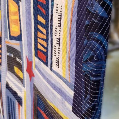 Détail de la pièce d'art textile Vous êtes ici. Vue du côté du tableau en perspective. Les tissus et le piquage se poursuivent jusqu'à l'arrière.