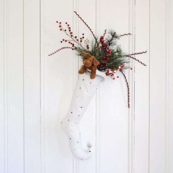 Christmas stocking Flake ornated with decorative accessories and a soft toy on a white door.
