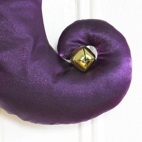 Detail of the Christmas stocking Tinkerbell, curved foot in purple taffeta with golden bell.