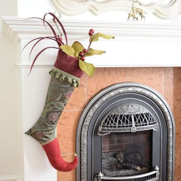 Elf stocking Theodora garnished with flowers and hanging to a fireplace.