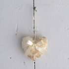 Coeur en tissu suspendu sur une porte. Tissu floral beige sur fond ivoire avec une boucle de satin ivoire.