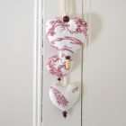 A trio of hearts Adelaide in red toile fabric on an off-white background, with wooden beads.