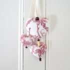 A trio of hearts in red toile on a white background. Floral motifs, wooden beads.