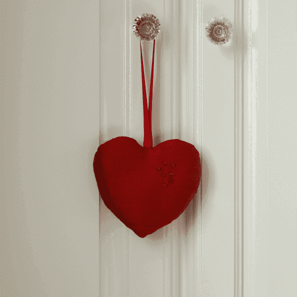 Red fabric heart hanging from the handle of a door.