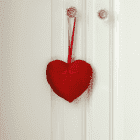 Coeur rouge en tissu suspendu à une poignée de porte.