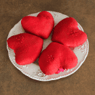 Quatre coeurs en soie rouge dans une assiette ivoire.