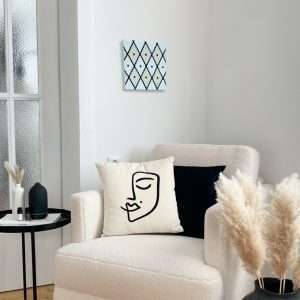 Tableau d'art textile Équilatéral sur un mur au-dessus d'un fauteuil