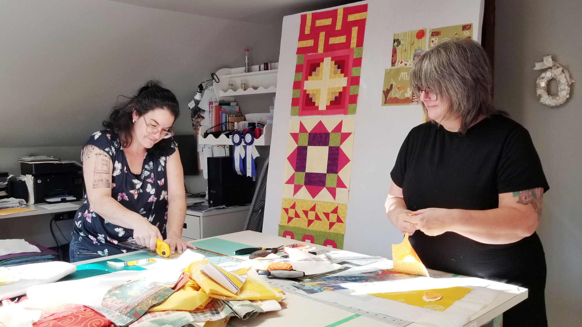 Two participants create small textile art pieces for a collective work of art in Christine Grenier's studio during the Récolte de rêves 2023 event.
