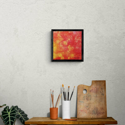 Tableau d'art abstrait rouge, jaune et rose sur le mur au-dessus d'une table.