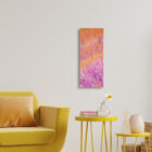 La mémoire du vent – Tableau textile abstrait, orange et mauve, installé dans un décor intérieur avec fauteuil et tables d’appoint jaunes.