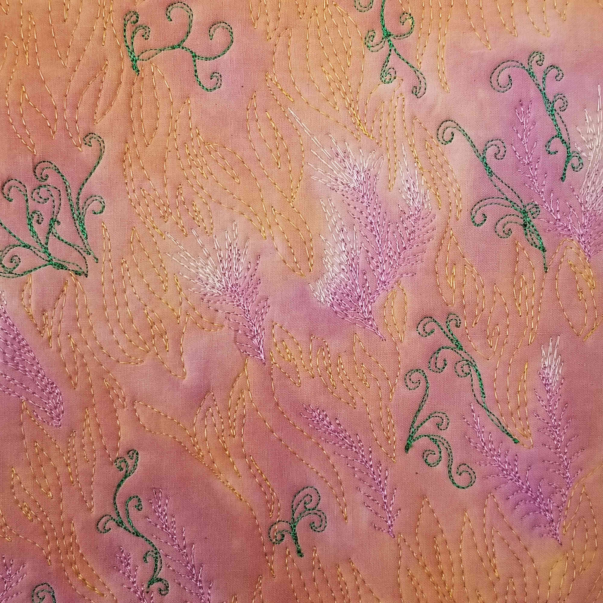 La mémoire du vent – Détail de broderie libre en fil orange, lilas et vert sur fond textile abstrait.