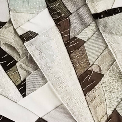 Détail du tableau textile Matin enneigé de Christine Grenier montrant les pièces de tissus, les broderies à la main et le piquage machine.