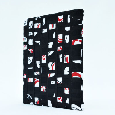 Perspective du tableau d'art textile En petits morceaux. Plusieurs petites pièces de tissu imprimé noir, blanc et rouge sont isolées sur un fond noir.