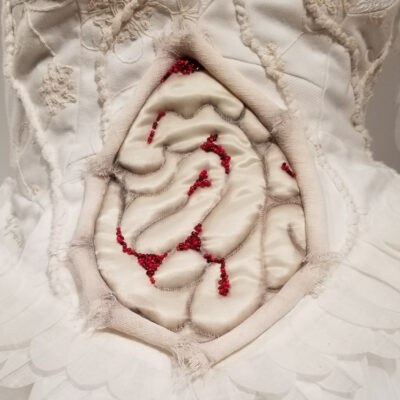Détail de la sculpture La Vainqueure montrant des entrailles avec des blessures de perles rouges à travers les couches de peaux ouvertes autour.